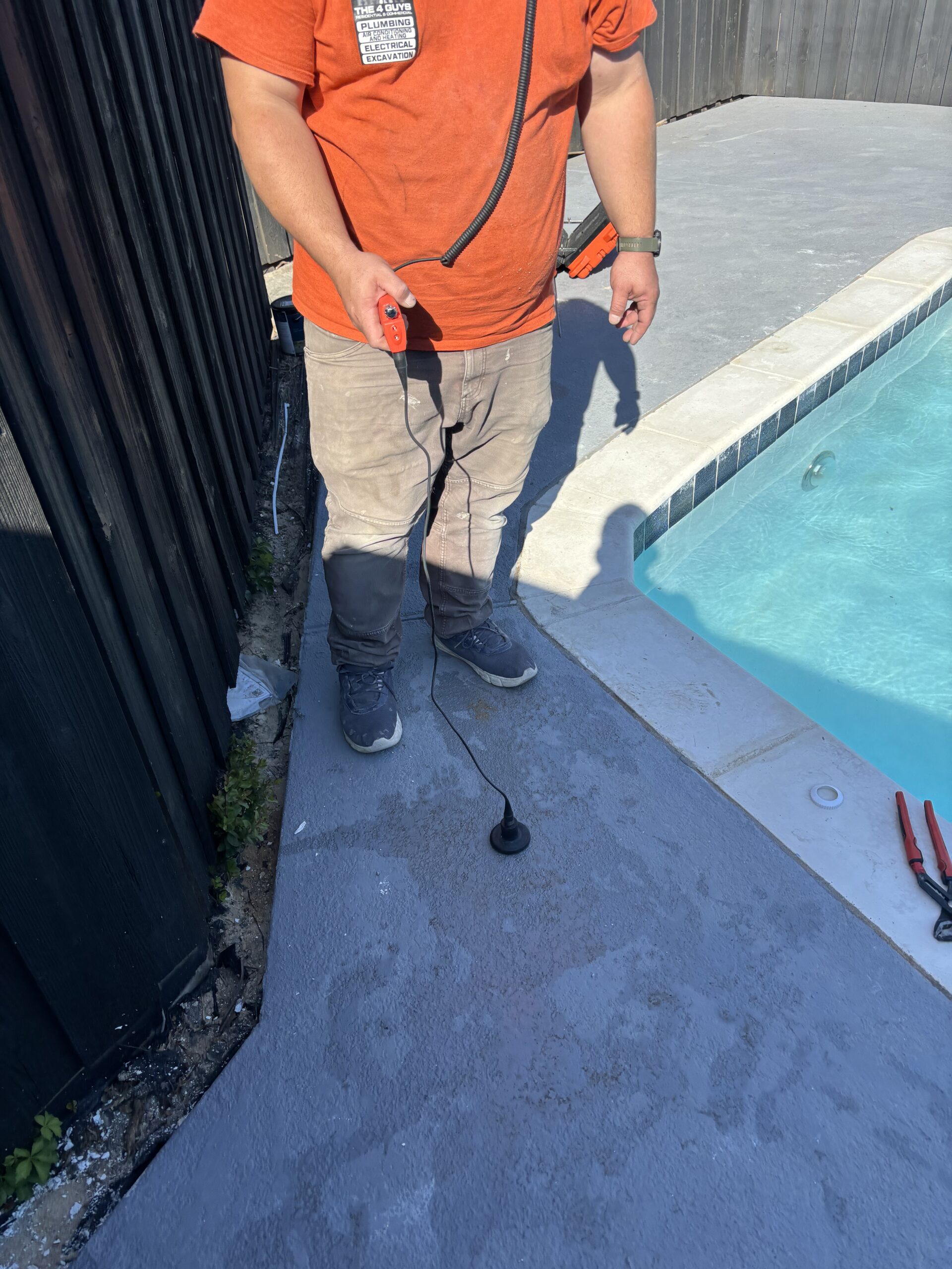 Technician positioning a listening sensor along a pool deck near the waterline