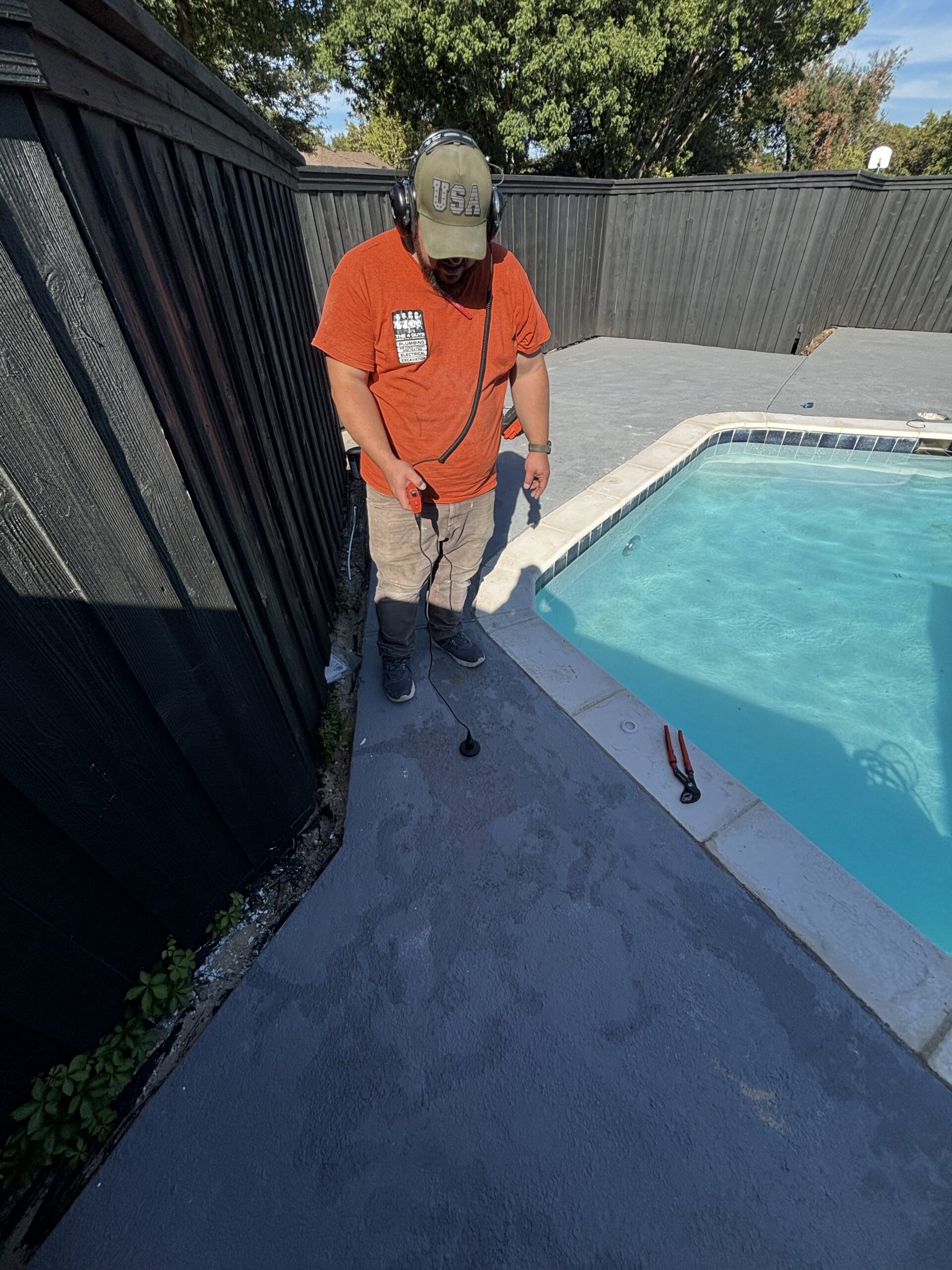 Pool leak detection technician using a deck-mounted listening sensor beside a swimming pool