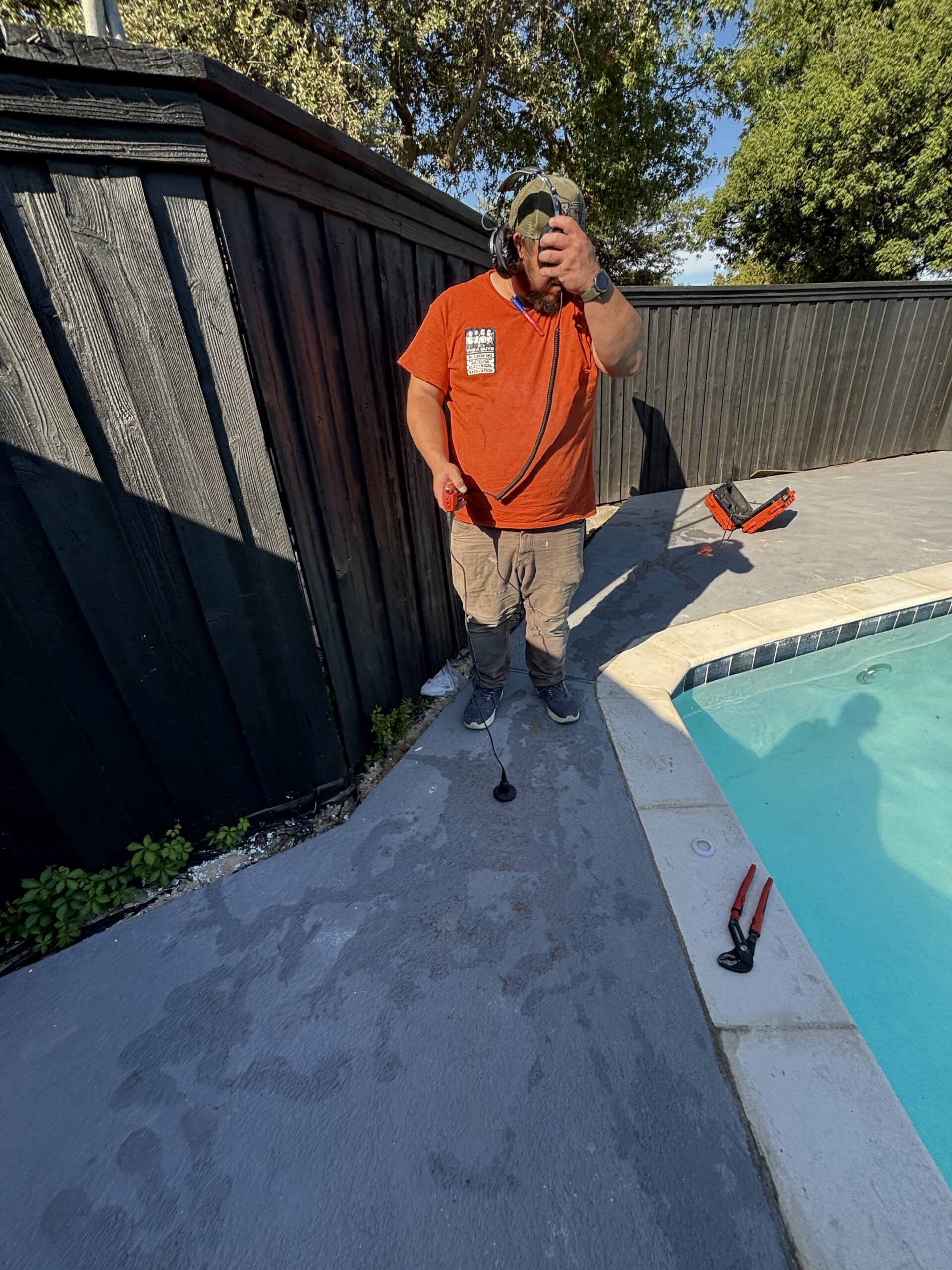 Pool leak detection technician holding electronic listening equipment beside the pool